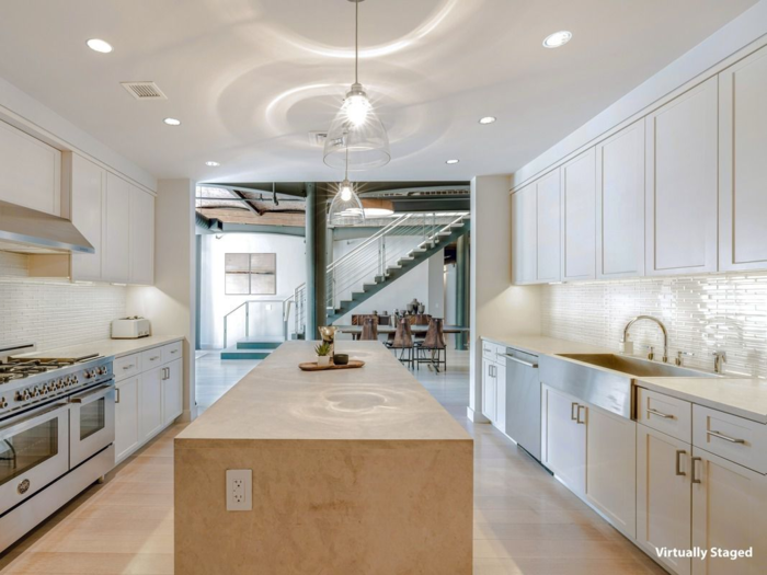 The double-oven kitchen features modern amenities and leads into a dining area with a staircase visible in the background.