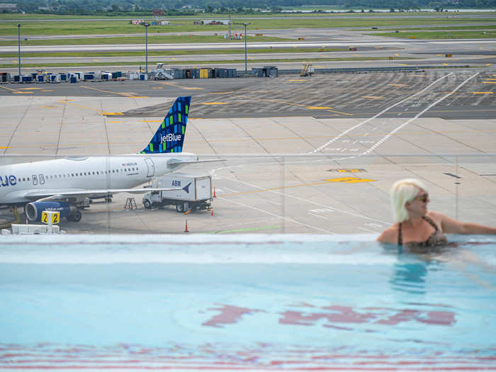 The red "TWA" logo in the middle of the pool helps blend the retro aesthetic with the rest of the hotel with the modern design and high-tech elements of the pool itself and the airport behind it.