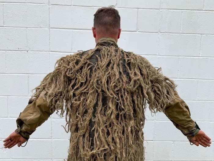 A ghillie suit, as can be seen here, is designed with loose strips resembling natural backgrounds like grass, and they can, when designed and implemented properly, make snipers nearly invisible in the visual spectrum.