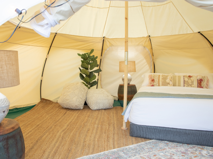 Inside the tent is a queen-size bed, lamps, and floor cushions.