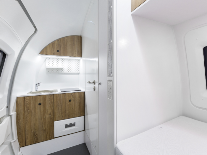 The pods include a work space, kitchenette, toilet, and shower.