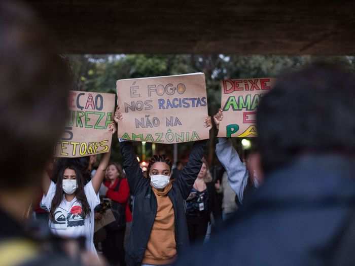 A group of young people held signs side-by-side. One reads, "Fire on racism, not in Amazonia."