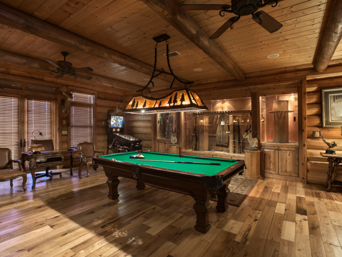 The billiard and game room includes a pool table, gun display cabinets, and a stone-lined fireplace. There’s also a wine cellar, gym, and a media room. The former leads into a porch with an outdoor kitchen.