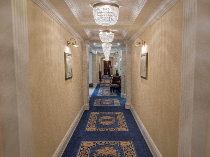 The hallway was carpeted in blue and gold and lined with glittering chandeliers.