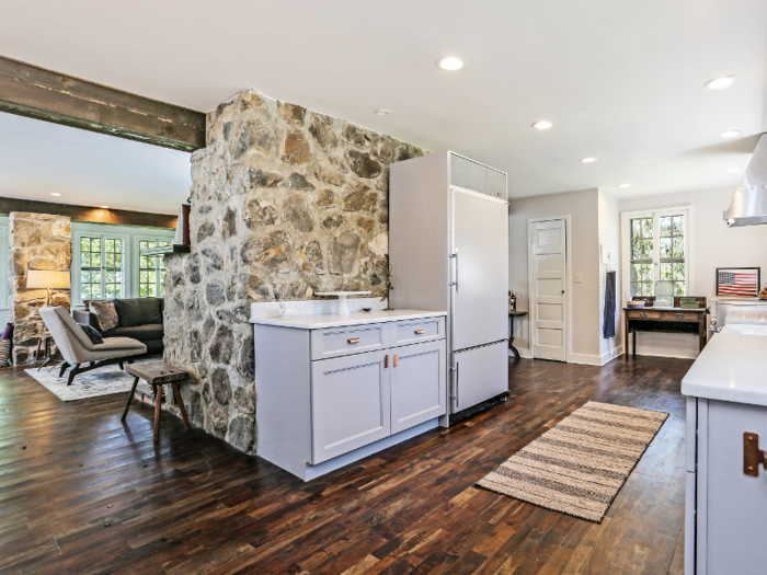 The living area and the kitchen area are separated by a stone wall.