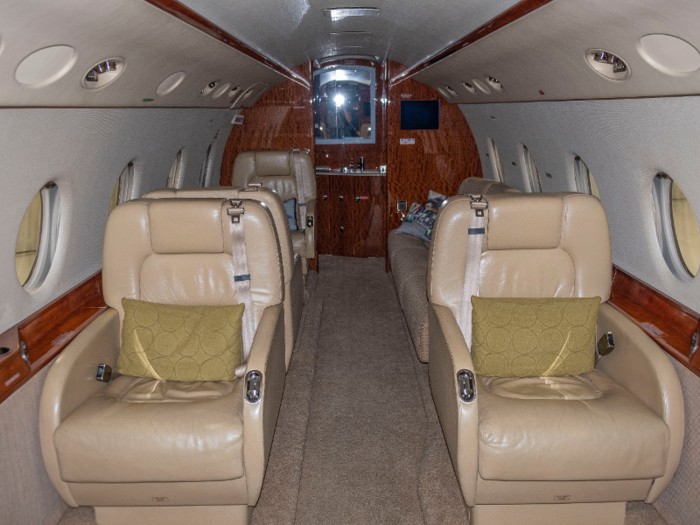 The interior is luxuriously appointed with beige leather seats and wood veneer.