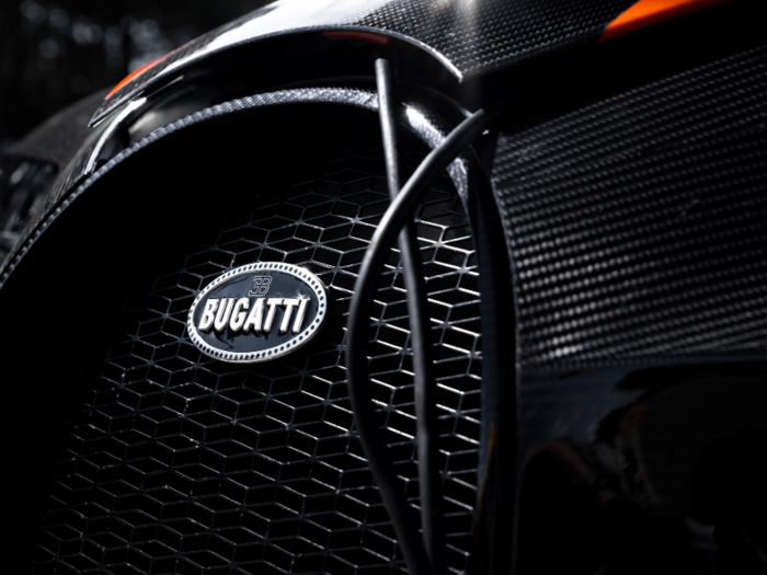 The chassis is made of jet-black carbon fiber, adorned with "Jet Orange" racing stripes. The Bugatti badge is crafted in a combination of silver and black enamel.