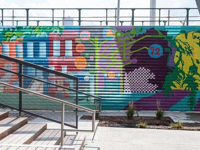 A mural, painted by apprentices from Creative Art Work, lines one side of the outdoor space. The mural is intended to reflect a Brooklyn aesthetic, situating Dock 72 in a specific place.