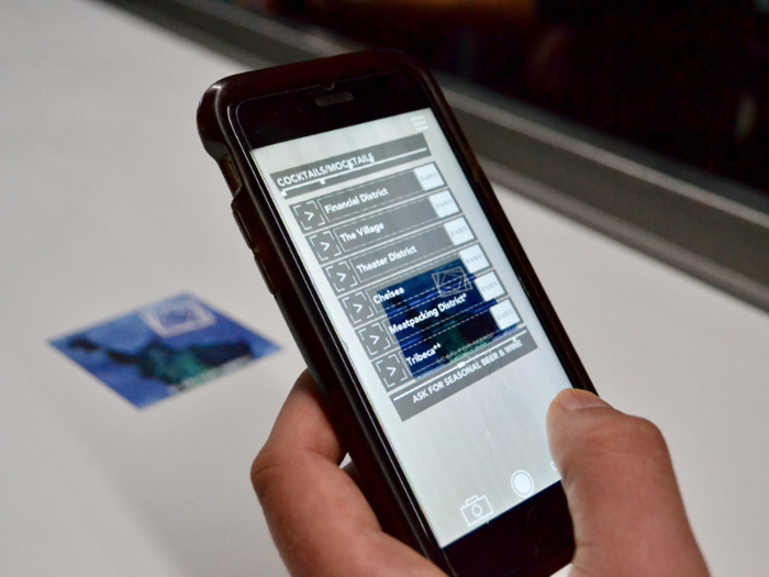 By downloading the Artechouse app and pointing your phone at a bar coaster, you can view the floating AR version of the cocktail menu. (Don