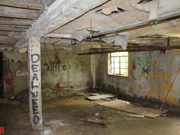 The old hospital (spanning 31,000 square feet) has a caved-in roof, missing doors, broken windows, and is covered in overgrowth.