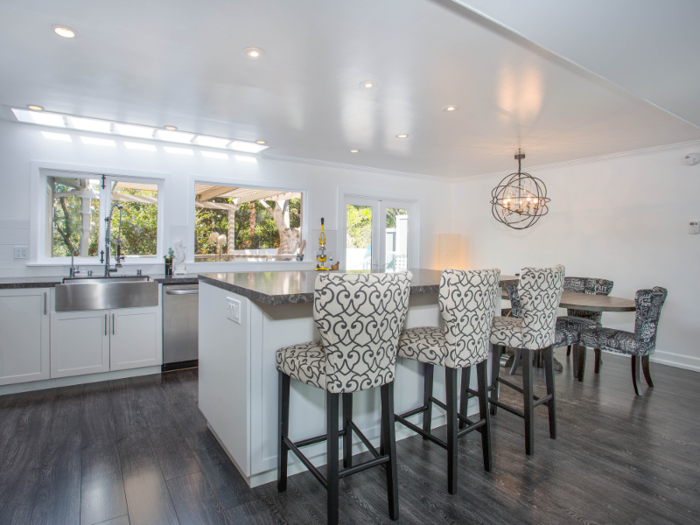 The living room opens up to a spacious kitchen, which boasts a large marble island that sits three and a table that sits six.