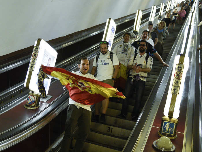 The escalators are well-lit, with illuminated advertisements on the sides. Here, a group of supporters of Spanish side Real Madrid enter a station ahead of the 2018 Champions League final, which was held in the city.