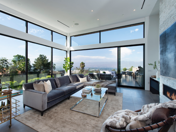 The spacious living area on the main level boasts various indoor seating options. An outdoor terrace is also accessible through the sliding glass doors adjacent to the sofa.