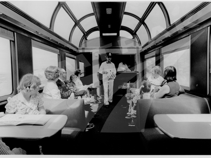 This photo, likely taken in the 1970s, depicts a steward in the dome lounge car playing a dining car chime to alert passengers of dinnertime. These cars were all retired by 1981.