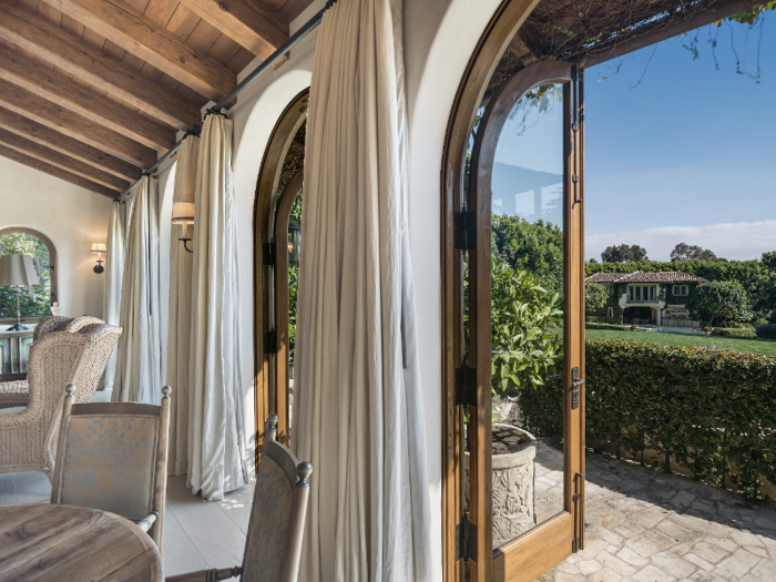 The two-story guest house, which can be seen across the lawn in the image below, sits adjacent to the pool and includes a bedroom, a bathroom, and a lower-level kitchen.