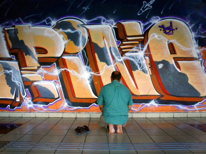 Even outside of the church, people find peaceful places to worship in this spacious station, like in front of this graffiti.