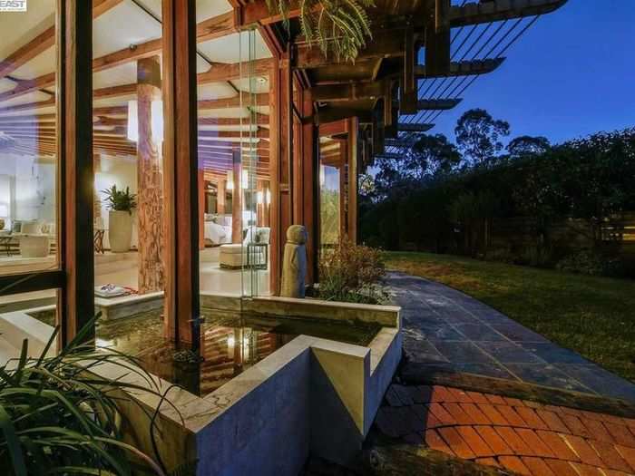 The water feature and glass walls create a continuous line between the indoor and outdoor living areas.