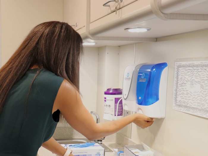 After each visit, Okon washes her hands and prepares to see her next patient.