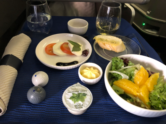 Then came the first course: Caprese salad and mixed greens. They offered three types of bread — pretzel roll, sourdough, and garlic bread. I went with the garlic bread.