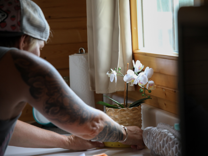 Draper fiddles with a pot of flowers under a windowsill and neatly organizes the incoming residents