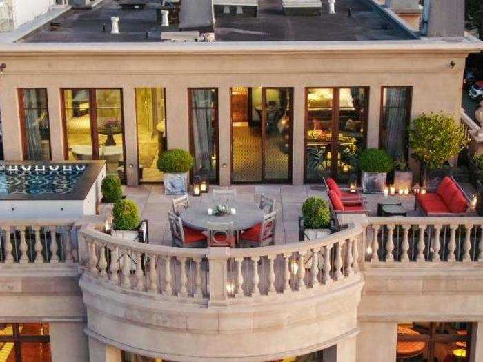 An upper balcony of the mansion features outdoor seating and a hot tub.