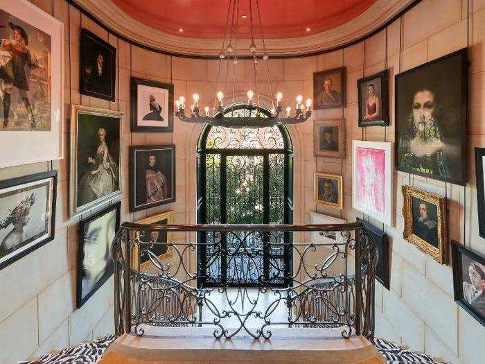 In the foyer, a double staircase with zebra carpeting is flanked with artwork.