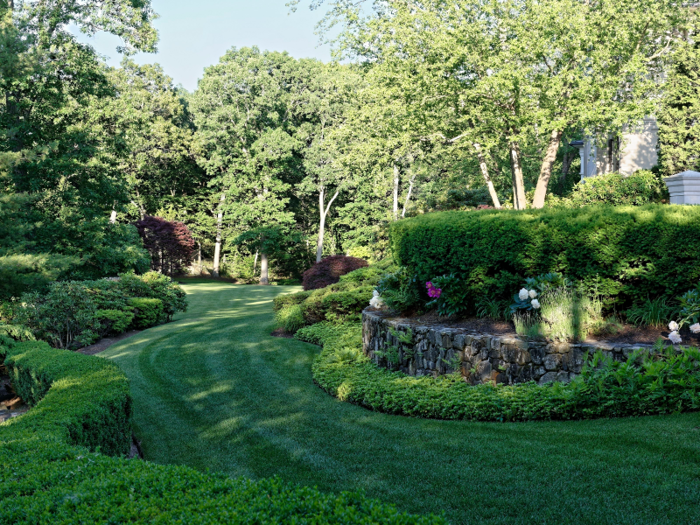 The grounds surrounding the home, which include trees, manicured gardens, and ponds and fountains, border the Country Club of Brookline.