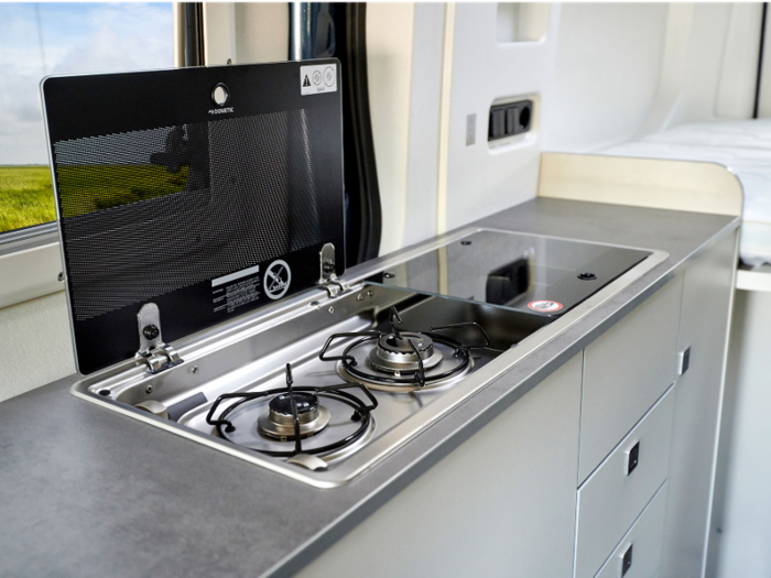 The kitchenette includes a two-burner gas stove, a sink, storage units, and a 70-liter, about 2.47 cubic feet, refrigerator. There’s also a hot water heater on the camper.