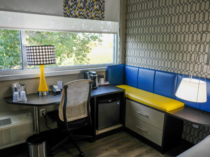 One corner of the room is occupied by a work station with a bench nook, storage drawers, and a mini-fridge.