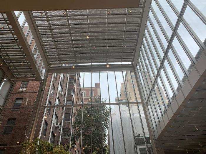 The entrance to library features an airy public atrium. Tall glass windows let you peer out at neighboring buildings in Manhattan.