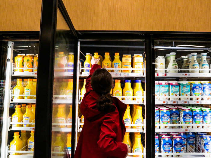 Shoshy stopped by the orange juice and milk fridge to pick up a bottle of Wegmans brand orange juice.