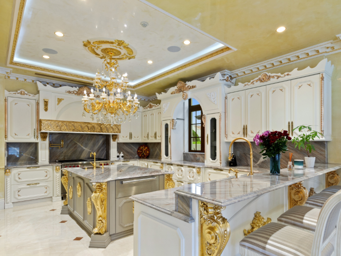 The kitchen features a marble-topped center island and golden hardware.