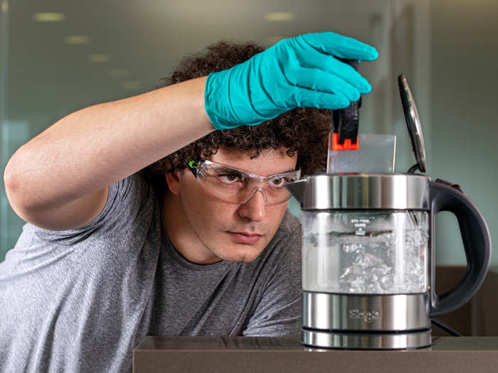 The glass can withstand being baked in an oven, microwaved, scoured with steel wool, demagnetized, and "other environmental threats." Here, a researcher douses the glass in boiling water to test its resilience.