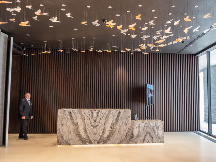 The lobby was minimalistic, with a blocky marble reception desk and a butterfly art installation hanging overhead.