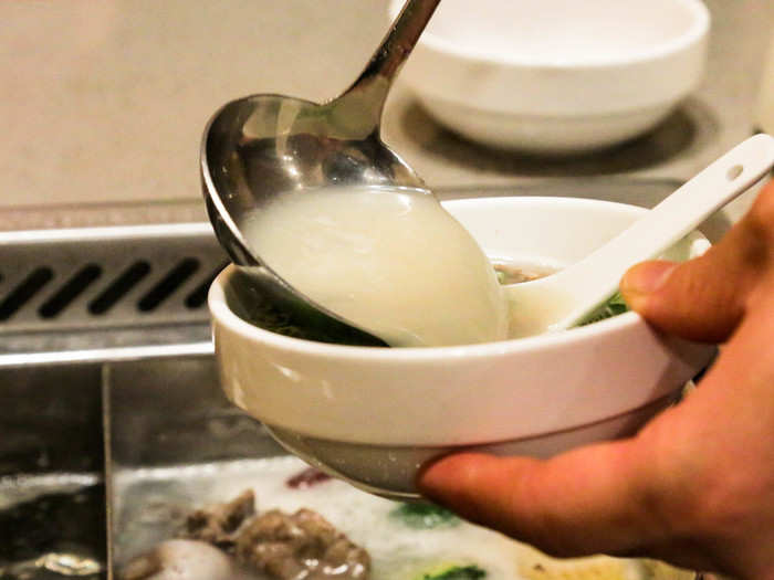 My waiter scooped out some pork bone broth for me into a bowl full of herbs and seasonings.