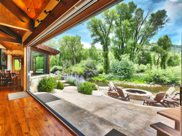 Pocket doors connect the living area to a riverfront stone patio complete with fire pit and spa.