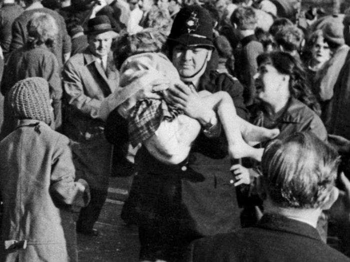 Here, a policeman named Victor Jones carries a little girl named Susan Maybank from the wreckage while a woman looks to see if she recognizes her.