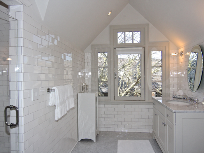 Listing photos show a minimalist bathroom with glossy white subway tiles.