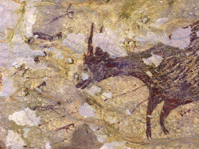 In part of the mural, a creature called an anoa, a relative of water buffalo, is surrounded by human-like figures carrying spears and possibly ropes.