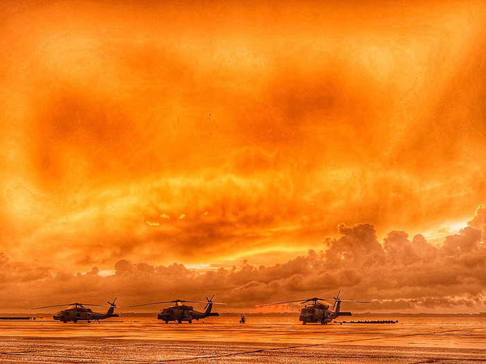 Three MH-60R Sea Hawk helicopters line the seawall at Naval Air Station Jacksonville as the sun rises over the St. Johns River on June 13, 2019.