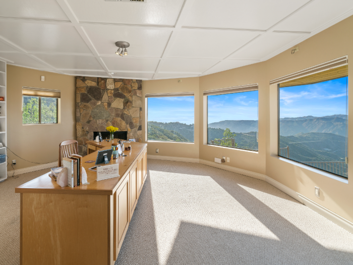 The study boasts a fireplace and large windows with views of the mountains.