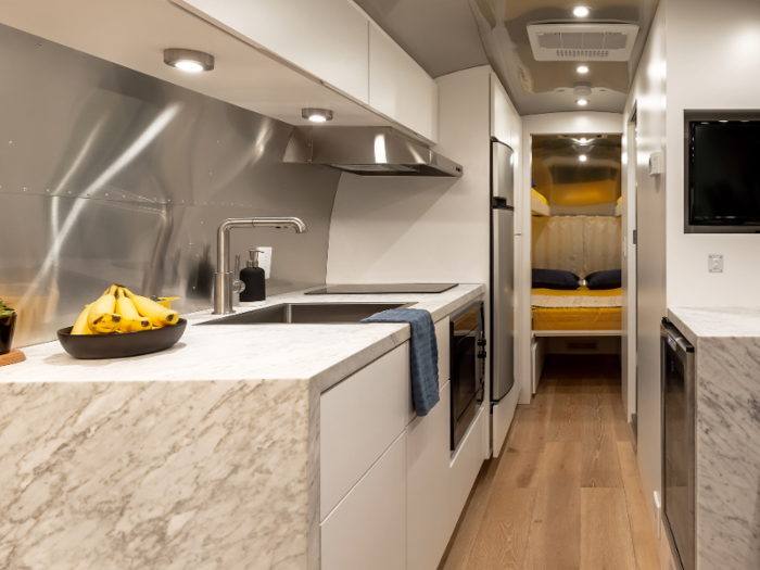 The kitchen includes a microwave, induction cooktop, and a refrigerator-freezer compartment.