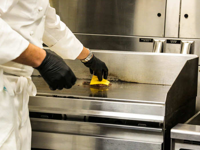 Then a slice of American cheese is added, and the patty sits for another minute and a half on the grill.