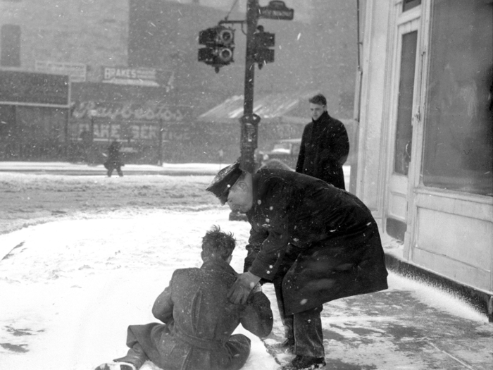 The conditions were often unkind to pedestrians. Here, a New York policeman helped a fallen man back to his feet on West Broadway.