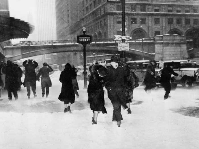 In 1935, people walked through a New York snowstorm. One woman buried her head in a man