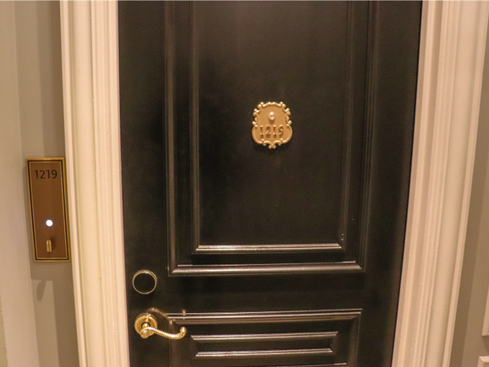 The doors to the rooms are glossy black with golden handles and numbered placards.