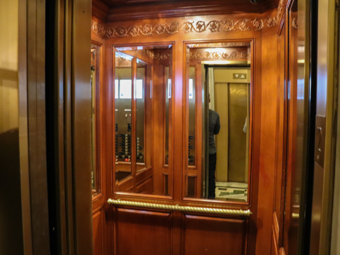 The elevators at the St. Regis, with their gilded exterior doors and interior wood paneling, evoke a different era.