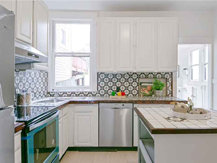 A blue-colored oven and intricately patterned backsplash add some pizzazz to the otherwise stark white kitchen.