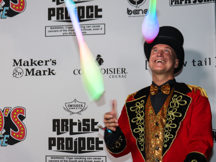 A circus performer wandered around on the red carpet, juggling glowing batons.