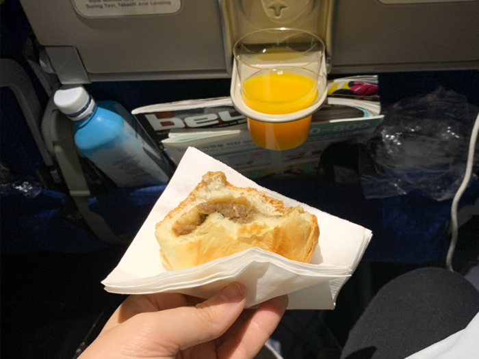 Seven and a half hours into the flight, attendants brought around rolls and juice. The roll was a pleasant, meat-and-carb filled affair, and I was able to use the mini cup holder for the juice. I downed it all and tried to fall back asleep.